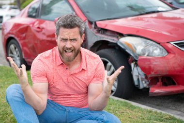 Stresli sürücü yolda kırık arabanın yanında oturuyor..