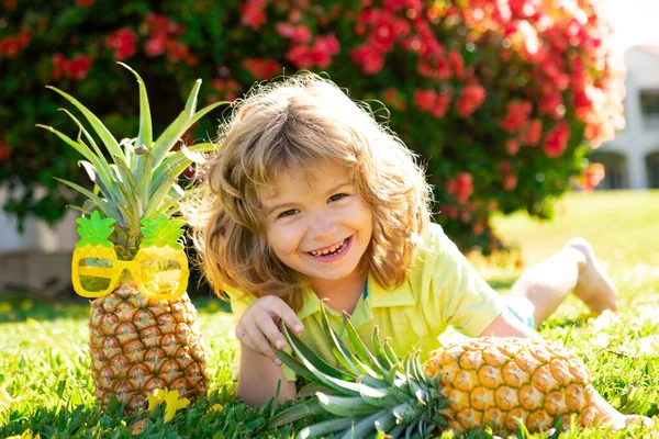 Portrait of little kid outdoors in summer. Smiling cute funny boy holding a pineapple. — Stock Photo, Image