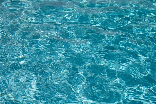 Modrý bazén vody pozadí. Rozmazaná průhledná, čistá a klidná struktura vodní hladiny. Vodní vlny ve slunečním světle s kopírovacím prostorem. — Stock fotografie