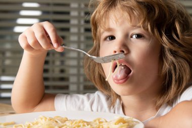 Makarna ve spagetti yiyen küçük şirin bir çocuğun portresi. Çocukluk kavramı.