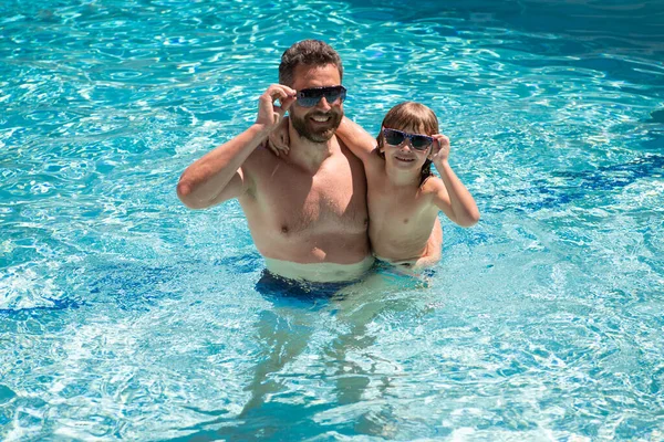 Father and son swimming in pool, summer family. Pool party. Family leisure. Summer vacation. Dad and son in pool.