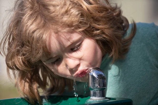 Пить хочется. Закройте голову снимком детской питьевой воды на улице в парке. Детское лицо, портрет мальчика. — стоковое фото