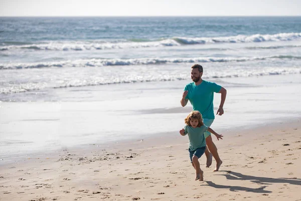 父と息子はビーチで走っている。スポーツと健康的なライフスタイル、ビーチでの家族のジョギング. — ストック写真