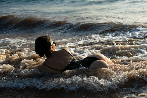 Back view sexy young woman posing on the beach. Beautiful woman relaxing at the ocean. Sexy curves girl butt.