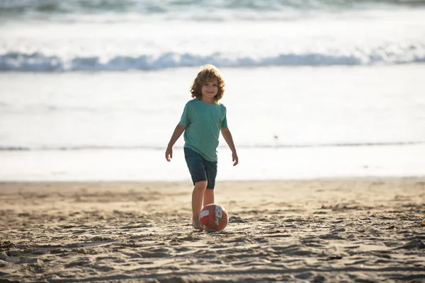 Barn pojke spela fotboll på sandstrand. — Stockfoto