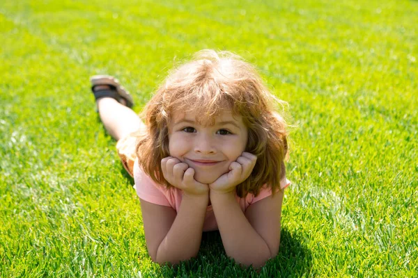 Närbild porträtt av ett gulligt barn som ligger i gräs i sommar naturpark. — Stockfoto