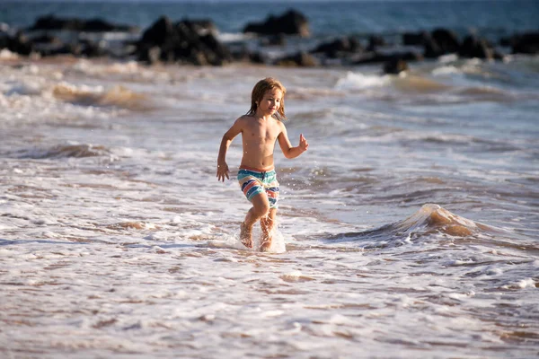 Bambino che corre sulla spiaggia tropicale. Ragazzo che gioca onde sul mare in vacanza mare durante le vacanze estive. Ragazzo in natura in riva al mare. Bambini che camminano al mare. — Foto Stock
