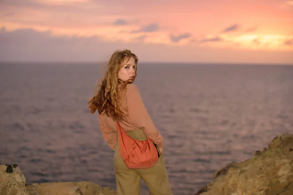 Frau im herbstlichen Kleid an der Küste des Ozeans, am felsigen Strand. — Stockfoto