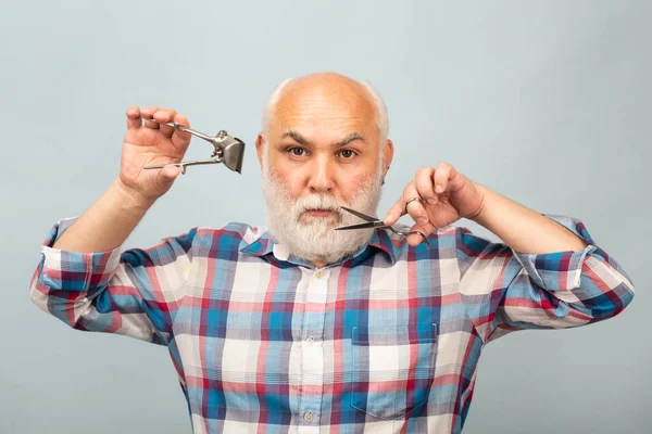 Портрет стильного чоловіка бородатого чоловіка з сірою бородою з вусами тримає ножиці і пряму зачіску для волосся з бритви . — стокове фото
