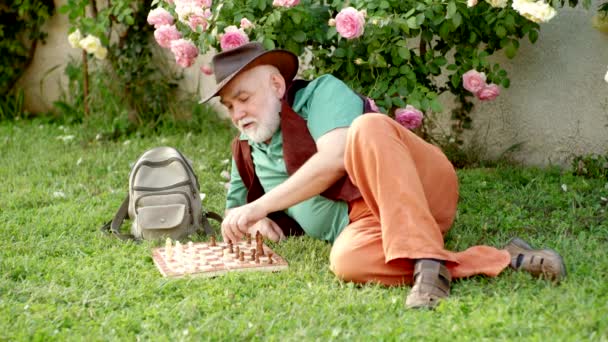 Un uomo maturo riposa in giardino. Nonno in giardino soleggiato piantare rose. hobby Giardinaggio. — Video Stock