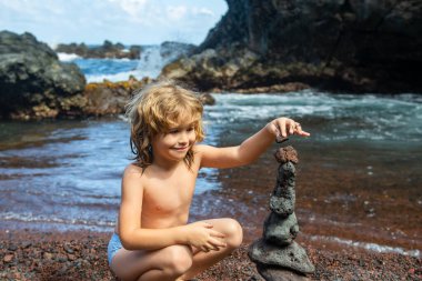 Çocuk öğrenme sıralaması ya da çakıl taşı kulesi ya da piramidi denge, eğitim ve doğa ile meditasyon için suya yığmak, çocuklar yaz tatilinde dinlenir.
