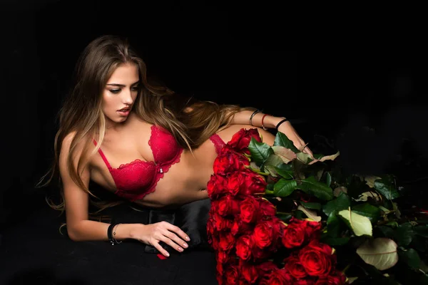 Schöne Frau mit Rosenblüten. Mädchen mit Rosenstrauß im Atelier auf schwarz. — Stockfoto