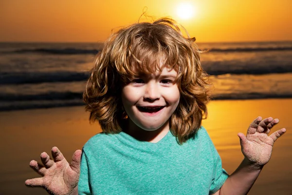 Pojkporträtt på solnedgångs stranden, tummen upp. Fantastiska överraskade barn känslor med fynny ansikte. — Stockfoto