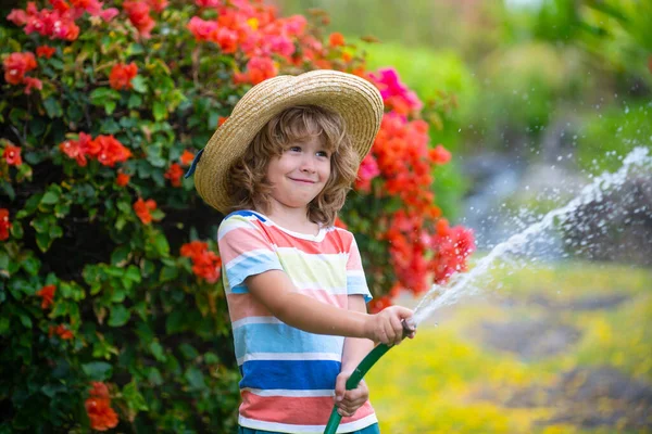 Повеселись. Смешной мальчик счастливо улыбается на природе. Малыш, повеселись на свежем воздухе. Быть смешным одна из моих сильных сторон. Полив растений в саду дома в летний солнечный день. — стоковое фото