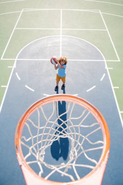 Çocuk bahçesinde basketbol oynayan çocuğun üzerinden açılı görüş.