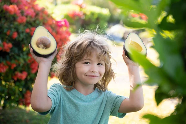 Kind eten en genieten van een avocado op een natuurlijke achtergrond. Gezond eten voor kinderen concept. — Stockfoto