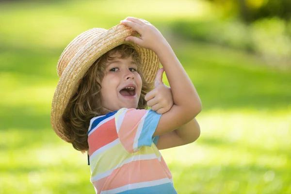 Porträtt av ett glatt skrattande barn i sommar naturpark med tummen upp skylt. Positiva ungar i halmhatt. Sommarsemester. — Stockfoto