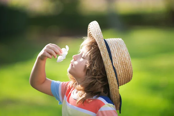 Ritratto ravvicinato di un bambino carino con cappello di paglia che profuma di fiore di plumeria. Concetto di infanzia e genitorialità. Vacanze estive. — Foto Stock