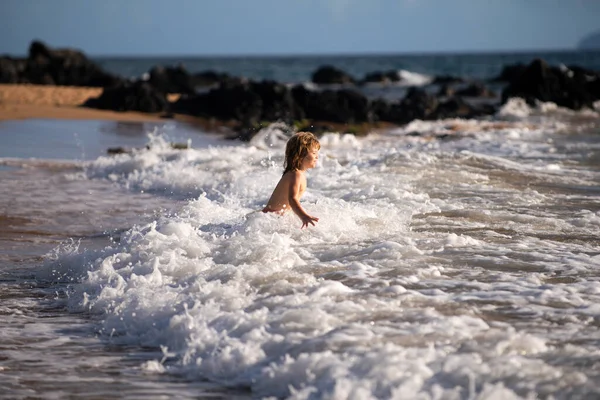 Menino ativo salpicando nas ondas do mar em um dia de verão durante as férias. O conceito de férias em família com crianças. — Fotografia de Stock