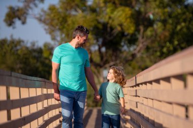 Baba oğul ağaçlık köprüde yürüyorlar..