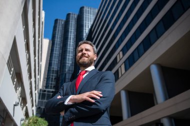 Yönetici işadamı. Modern ofis yakınlarında takım elbiseli bir CEO portresi. Şirket binasının önünde duran mutlu lider..