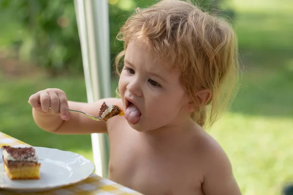Schattig kind eet dessert op zonnige zomerdag, natuurlijk buiten. Babytaart eten. — Stockfoto