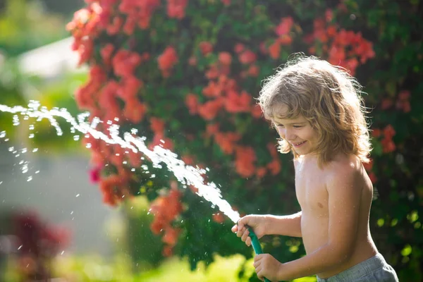 Diviértete. Chico divertido feliz sonriendo en el paisaje natural. Niña, diviértete al aire libre. Ser gracioso es una de mis mayores fortalezas. Riego de plantas en el jardín en casa en verano día soleado. —  Fotos de Stock