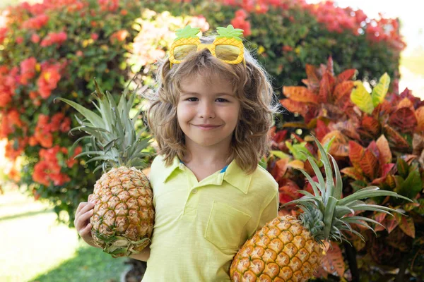 Retrato de criança pequena ao ar livre no verão. Sorrindo bonito engraçado menino segurando um abacaxi. — Fotografia de Stock