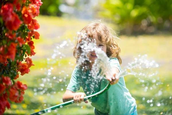 Kids play with water garden hose in yard. Outdoor children summer fun. Little boy playing with water hose in backyard. Party game for children. Healthy activity for hot sunny day. — Stock Photo, Image