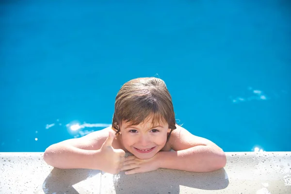 Criança caucasiana na piscina. Os miúdos levantam os polegares. Kid relaxar no lado da piscina. — Fotografia de Stock