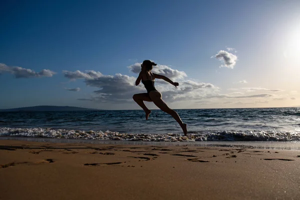 Femme coureuse sur la plage. Femme courant au coucher du soleil sur la plage. Sport d'été et concept de liberté. Entraînement des athlètes au crépuscule. — Photo