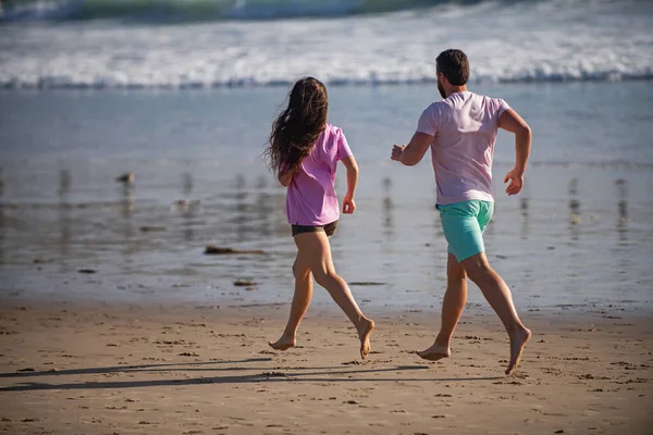 Couple courant sur la plage. Courir les gens faire du jogging sur la plage faire de l'exercice et faire du jogging. Les coureurs sportifs travaillant sur la plage d'été. — Photo