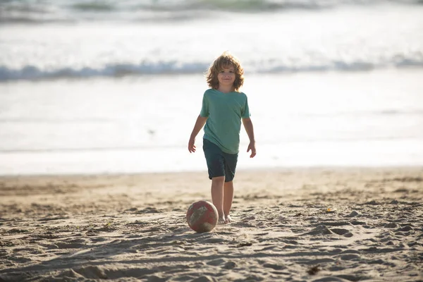 Liten pojke barn spela fotboll på kusten av havet stranden. Sommar barn sport. — Stockfoto