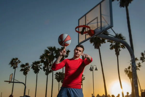 Баскетболист с баскетбольным мячом на улице. Крутящийся мяч. Балансировка на пальце. — стоковое фото
