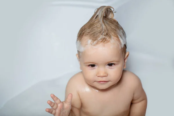 Maluch pod prysznicem. Dzieciak w wannie z puszystą bańką mydlaną. Szczęśliwe dziecko biorące kąpiel bawiąc się bańkami z pianki. Małe dziecko w wannie. Mycie i kąpiel niemowląt. Opieka nad dziećmi i higiena. — Zdjęcie stockowe
