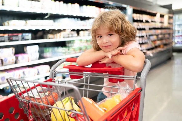 Bambino carino con carrello della spesa al negozio di alimentari o al supermercato. — Foto Stock