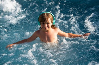 Mutlu çocuk suda eğleniyor ve yaz tatilini havuzda geçiriyor. Mutlu tasasız çocukluk kavramları. Yaz tatili.