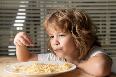 Makarna ve spagetti yiyen küçük sarışın bir çocuğun portresi. Komik çocuk suratı.