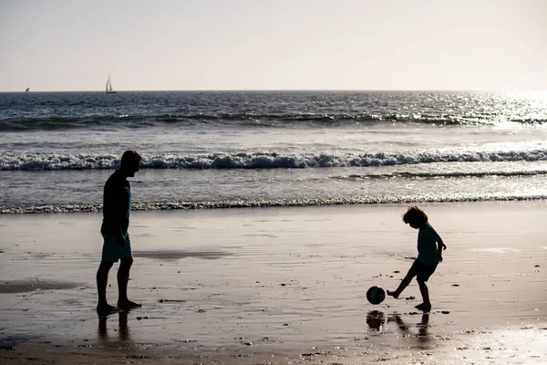 父と息子はビーチでサッカーやサッカーをします。フレンドリーな家族と夏休みの概念. — ストック写真