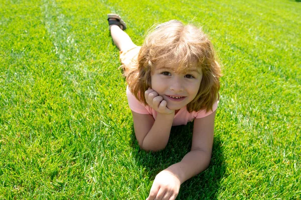 Porträtt av en liten pojke som ligger i gräs. Porträtt av barn. — Stockfoto
