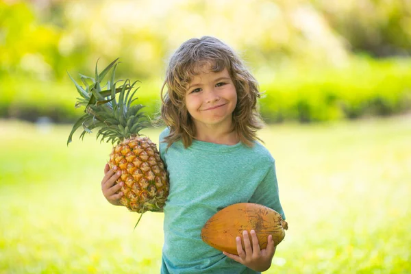 Barnpojke med ananas och kokosnöt leende med glatt ansikte. Sommarfrukter. — Stockfoto