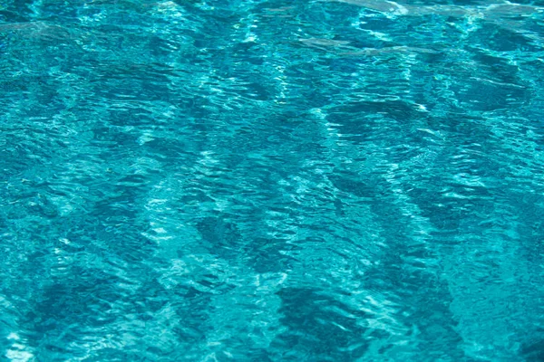 Fondo de agua azul en la piscina con reflejo solar, ondulación de la ola de agua en la piscina. Fondo de agua clara. — Foto de Stock