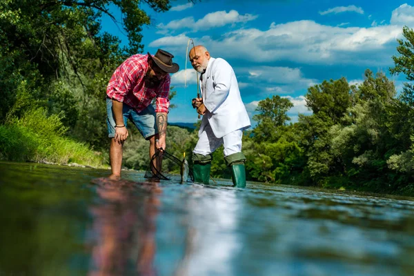 Padre e figlio adulto pesca sul lago. Mi sto divertendo. Attrezzatura da pesca Fisher. Dare il tuo hobby. Padrone Baiter. Sono l'uomo piu 'felice. Pescatore cattura il pesce. Brutale uomo stare in acqua di fiume. — Foto Stock