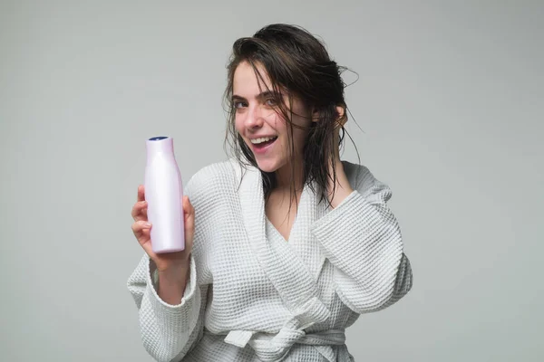 Belle femme caucasienne posant avec les cheveux mouillés. Femme tenir bouteille shampooing et revitalisant. Jeune femme publicité produit de soins. — Photo