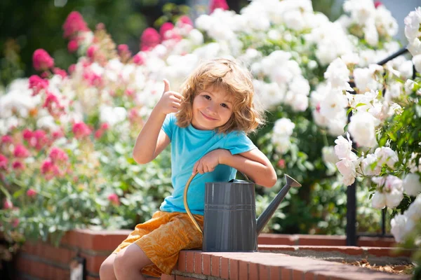 Милый забавный ребенок в саду в весенний день. Пальцы вверх. — стоковое фото