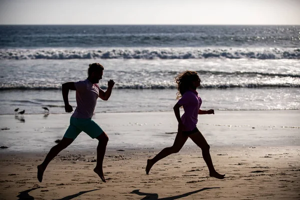 Paar läuft am Strand. Sport und gesunder Lebensstil, Freunde der Silhouette joggen bei Sonnenuntergang am Strand. — Stockfoto