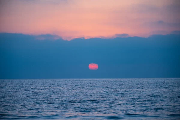 Gün batımında gökyüzü ve bulutların arasında güneş olan sakin bir deniz. Okyanus ve gökyüzü arkaplanı, deniz manzarası. — Stok fotoğraf