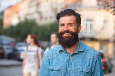 Kot ceket giymiş yakışıklı, güler yüzlü, şık bir adam. Sokak arka planında poz veren şehirli moda erkeği..