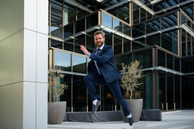Businessman running in city is happy to succeed in his work. Business man winner.