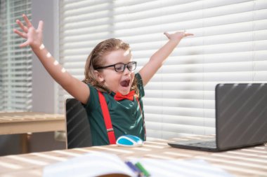 Öğrenci çocuk internetten bilgisayar kullanarak ders çalışıyor. Bilgisayar kullanarak online okula giden çocuk.